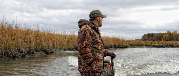 Man in camouflage clothes hunting in a body of water